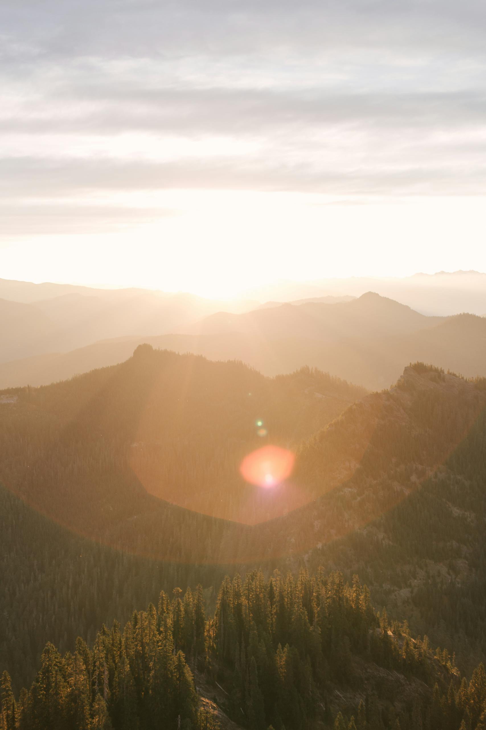 Breathtaking sunrise over Mount Rainier showcasing misty mountains and vibrant sunrays.