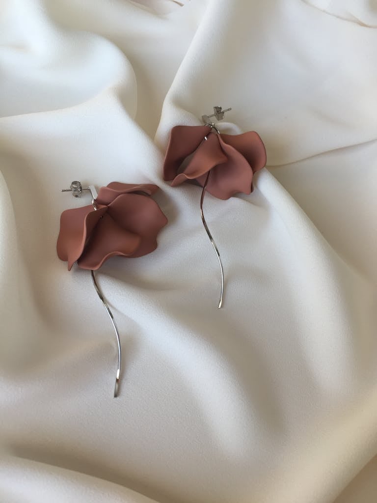 Elegant floral earrings on soft white fabric, showcasing delicate design and craftsmanship.