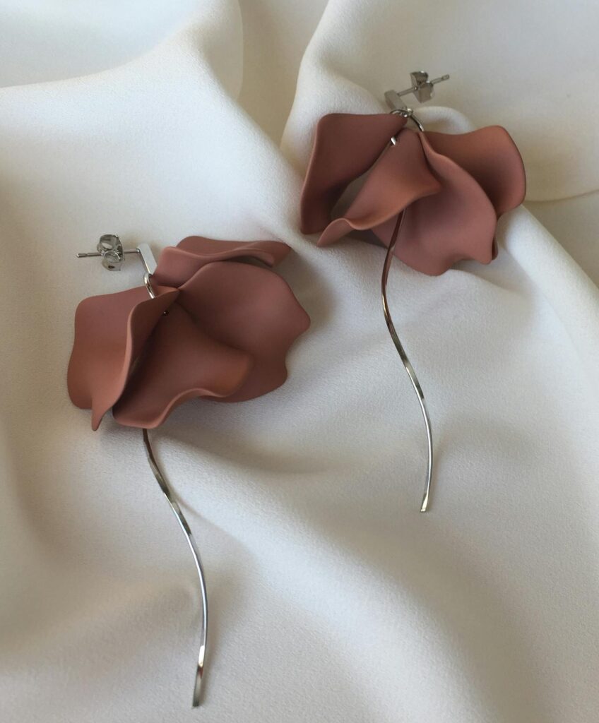 Elegant floral earrings on soft white fabric, showcasing delicate design and craftsmanship.