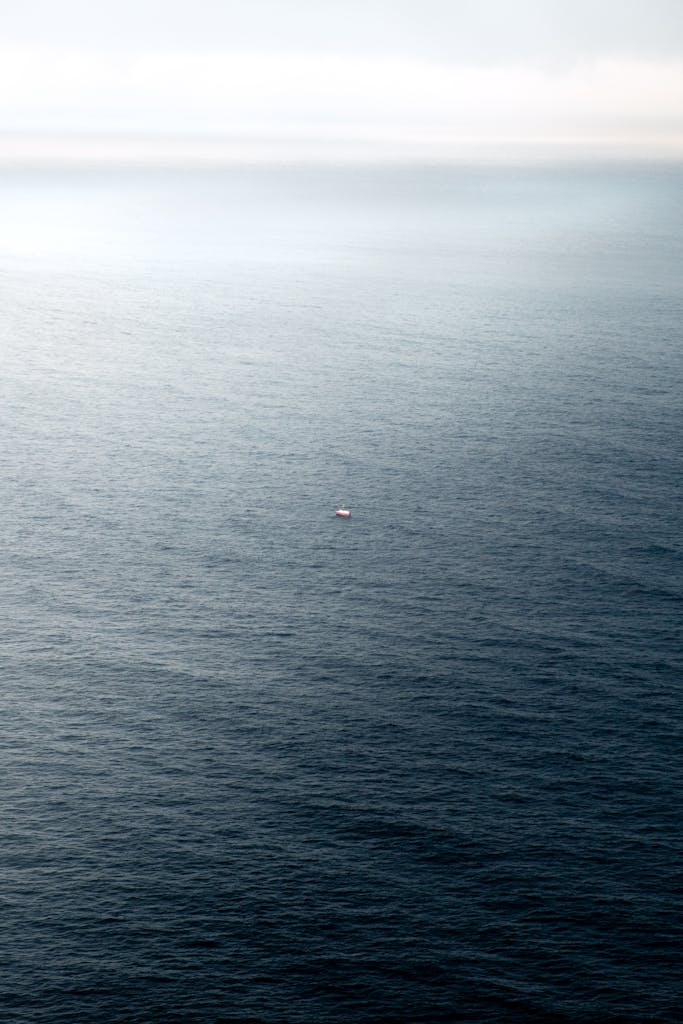 Stunning aerial shot of endless ocean with a lone boat, capturing the vastness and solitude of the sea.