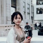 Woman with short hair holding a smartphone on a city street in Wuhan, China.